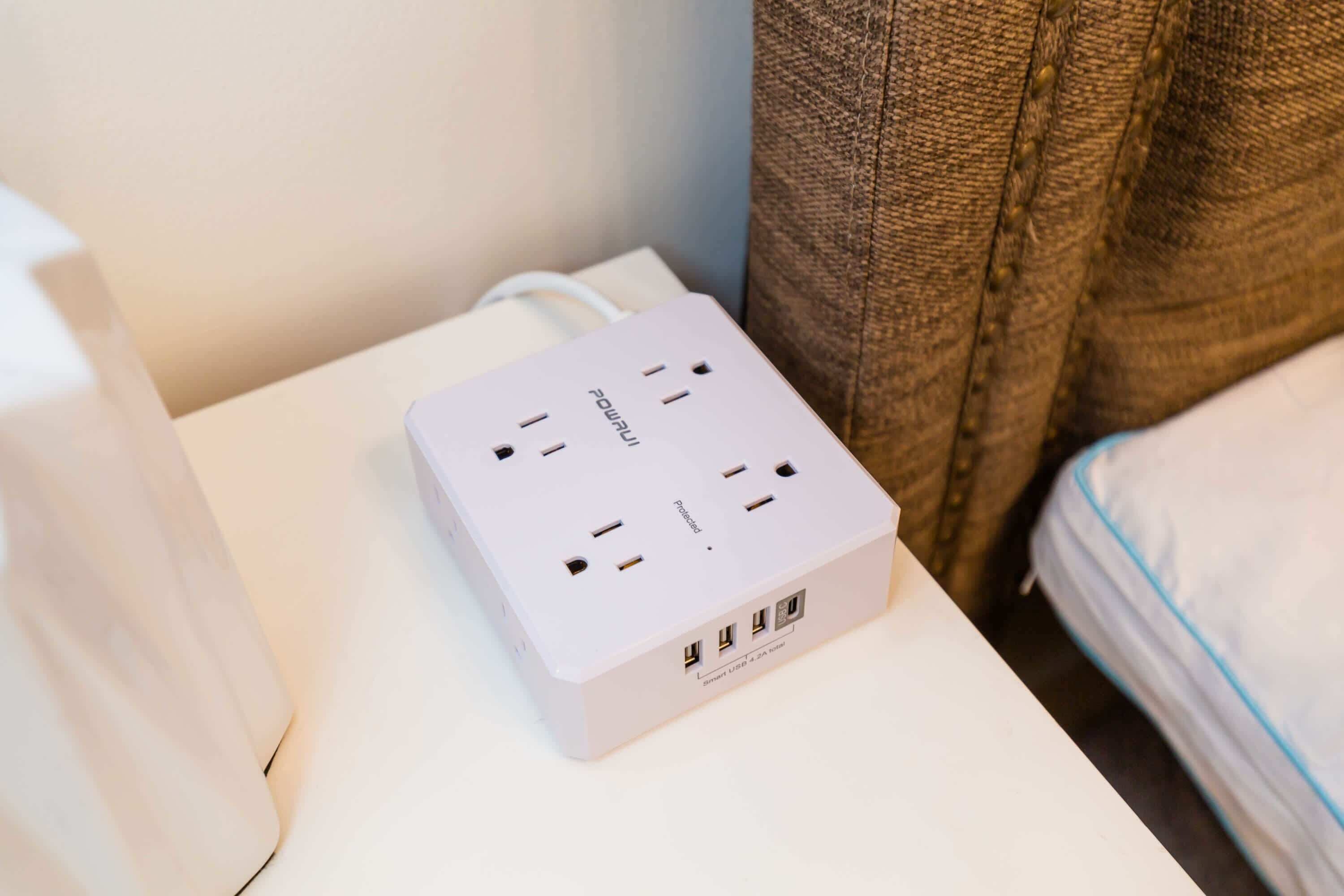 Eine weiße Mehrfachsteckdose mit mehreren USB-Anschlüssen und einem Aufkleber, der sie als Smart USB 2.0 kennzeichnet, an einer Wand.