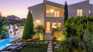 A modern two-story house with a swimming pool, a well-maintained garden, and a barbecue area.