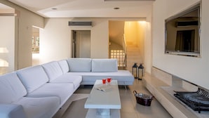 A modern living room with a white sectional sofa, a coffee table, and a staircase leading to an upper floor.