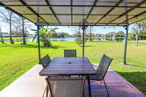 An outdoor patio with a table and chairs, overlooking a lake and greenery. - *NrDisney&Universal*NewlyRenovated*LakeFront*APT (Kissimmee)