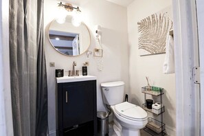 A modern bathroom with a round mirror, white toilet, and black cabinet. - *NrDisney&Universal*NewlyRenovated*LakeFront*APT (Kissimmee)