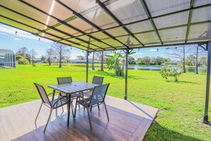 An outdoor patio with a table and chairs, a covered area, and a view of a lake and park. - *NrDisney&Universal*NewlyRenovated*LakeFront*APT (Kissimmee)