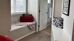 A hallway with a window seat, a door, and a patterned pillow. - Boise Avenue Getaway • 3BR/3BA • Yard • Parking for 2 • Near BSU & Downtown • Spacious (Boise)