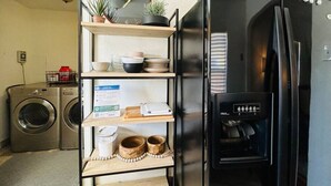 Eine kompakte Küche mit integriertem Kühlschrank, Waschmaschine und einer Küchenzeile mit verschiedenen Küchenutensilien.