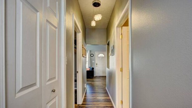 A hallway with white doors, a wooden floor, and a ceiling light fixture. - The Red Bench Cottage | Historic Charm • Fenced Yard • Walk to Hyde Park • Central Boise (Boise)