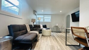 Una sala de estar moderna con un conjunto de sofá, una mesa de centro redonda y un comedor con mesa y sillas.