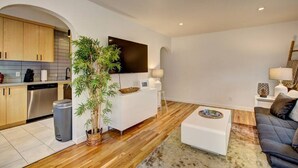 Una sala de estar moderna con un sofá blanco, una mesa de centro y un televisor montado en la pared.