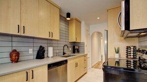 Una cocina moderna con armarios de madera, lavavajillas, cafetera y estante para vinos.