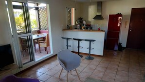 Una cucina con zona pranzo, TV e una porta scorrevole in vetro che dà su un patio esterno.