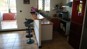 Una cucina compatta con isola centrale, un frigorifero rosso e un'area pranzo con sgabelli da bar.