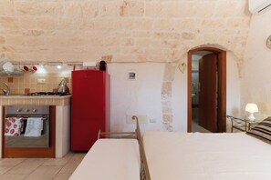 Cocina compacta con estufa a gas, un refrigerador rojo y comedor con mesa y sillas.