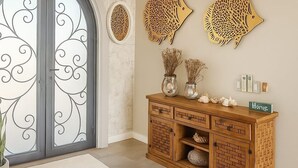 A foyer with a marble wall, a wooden cabinet with decorative items, and a chandelier. - Casa Marimar with private heated pool at Laguna Shores Resort (Puerto peñasco)