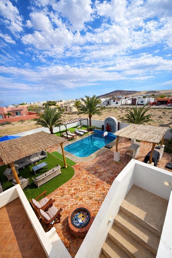 A rooftop pool area with a view of the surrounding landscape, including buildings and hills.