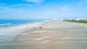 Une vaste plage de sable fin, avec un ciel dégagé et une mer limpide.