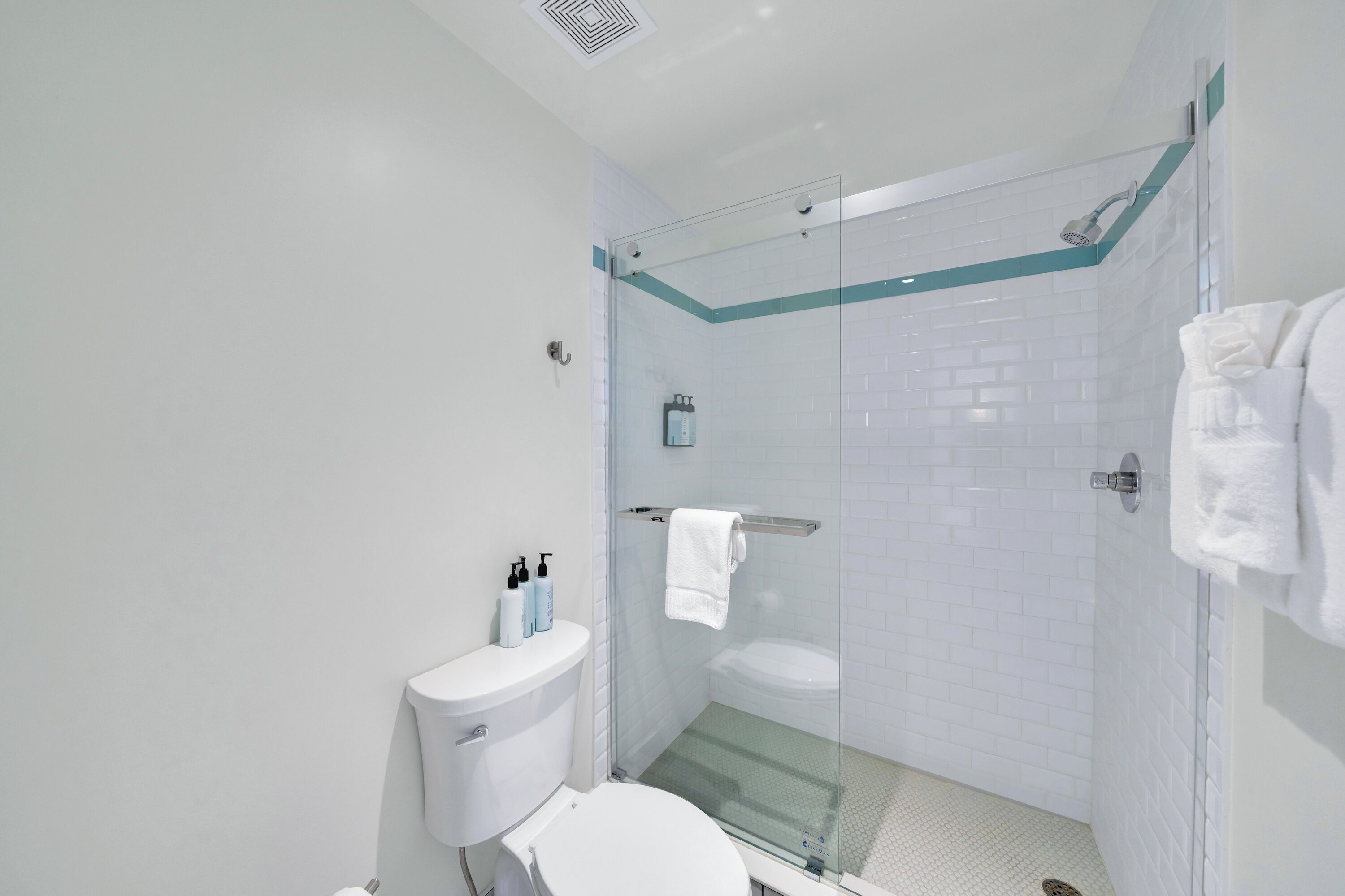 Een moderne badkamer met een douchecabine van glas, een toilet en een handdoekhouder.