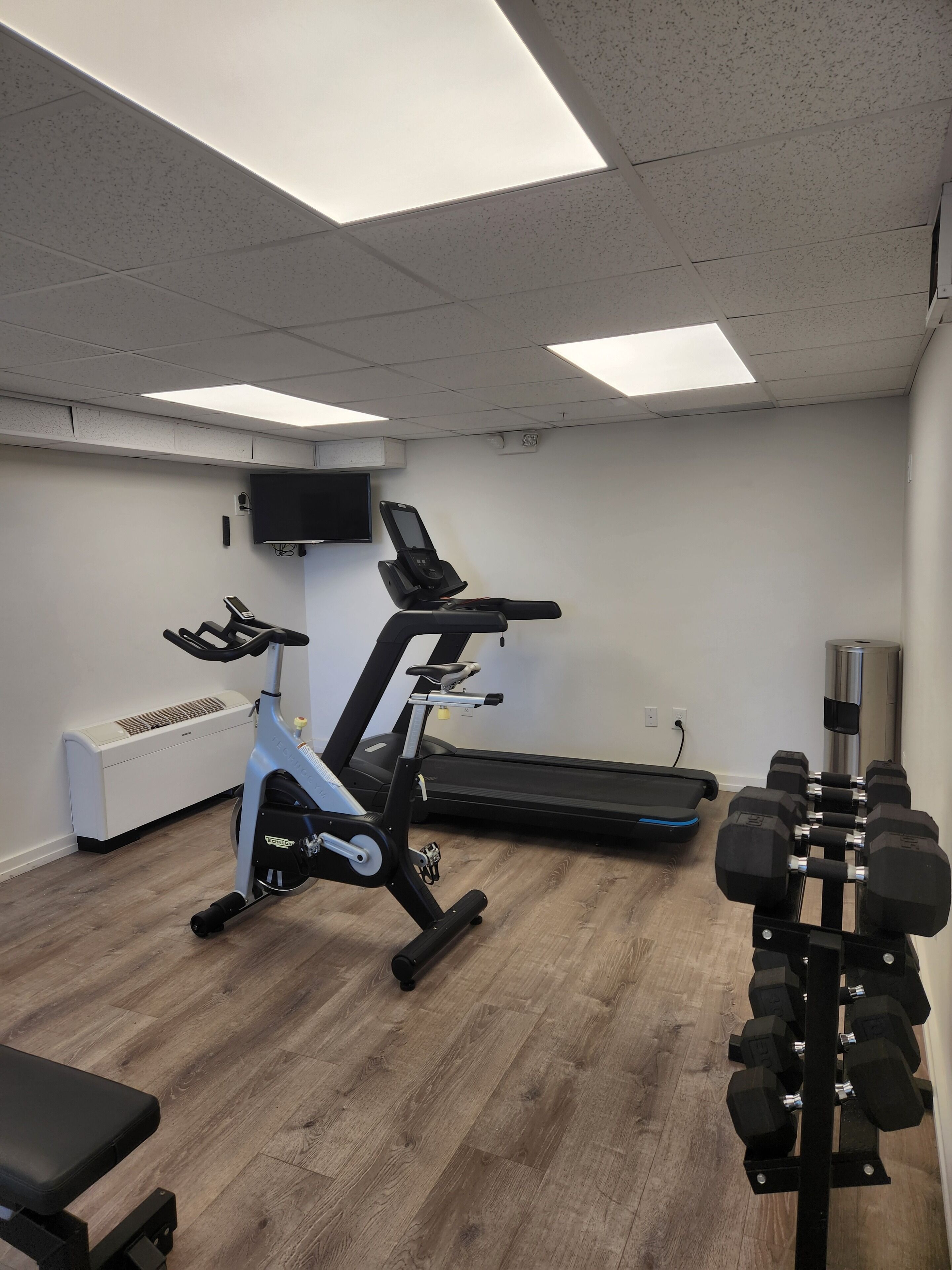 A gym with exercise equipment including a treadmill, stationary bike, and dumbbells.