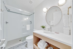 Une salle de bain moderne avec une douche à parois de verre, des toilettes et un lavabo avec un miroir au-dessus.