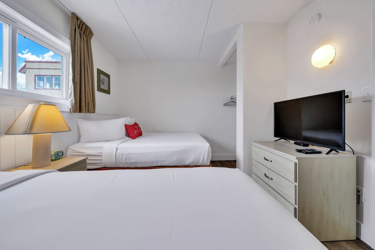 Ein Hotelzimmer mit einem Bett, einem Schreibtisch mit Lampe, einem Fernseher und einer Kommode.