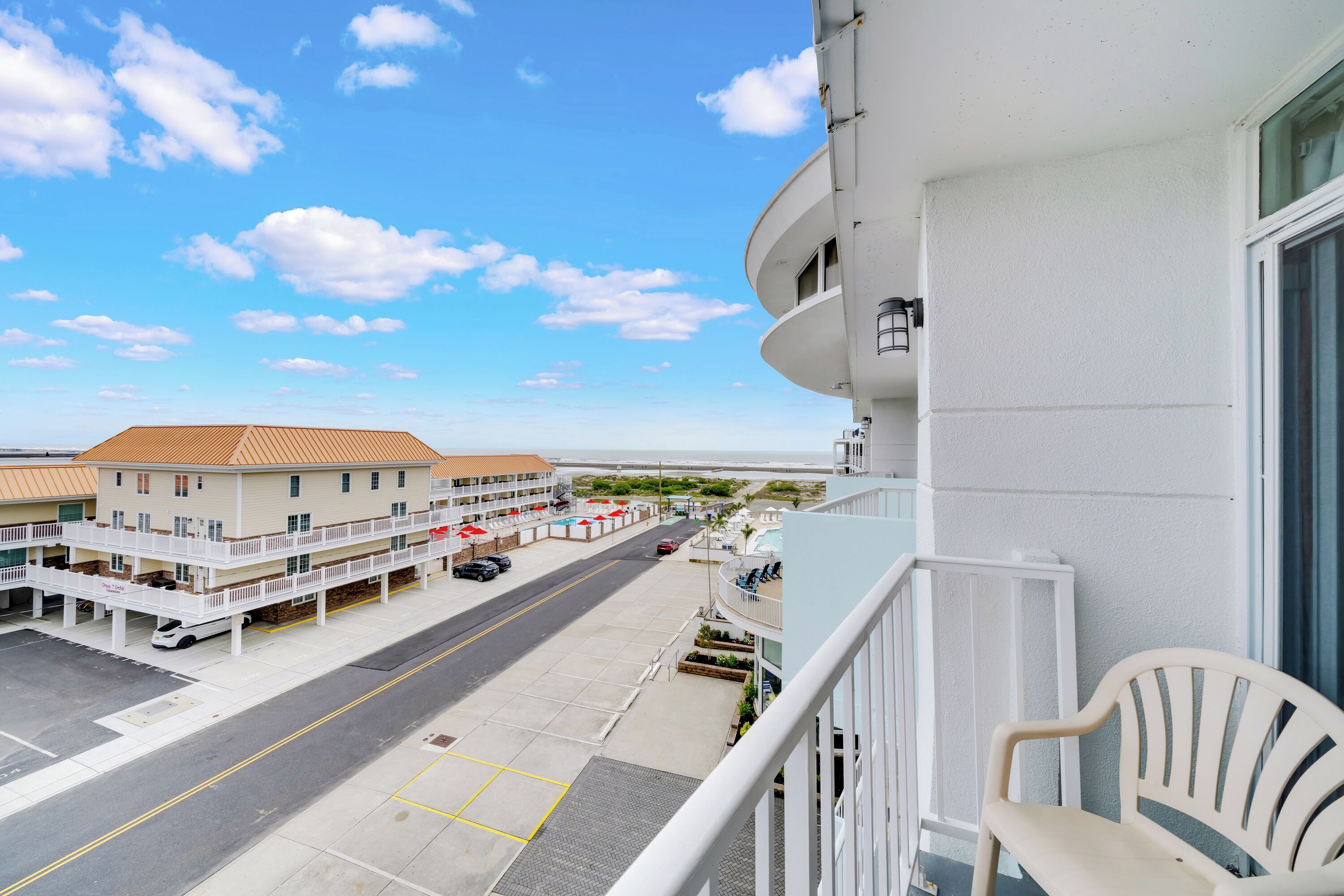 A hotel with a balcony, a parking area, and a view of the beach.
