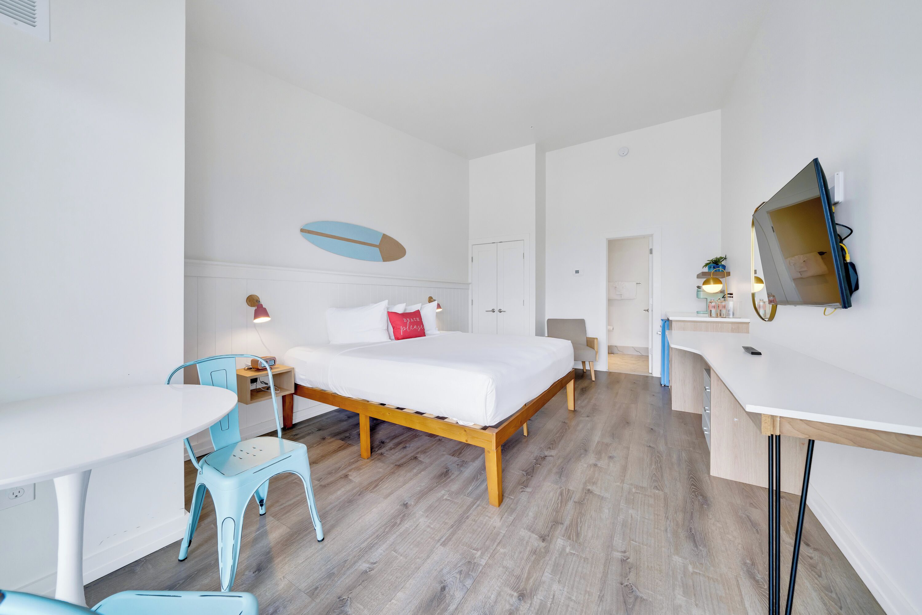 A modern hotel room with a bed, a desk, a chair, and a dining table.