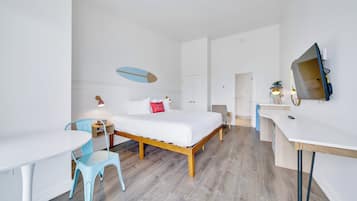 A modern hotel room with a bed, a desk, a chair, and a dining table.