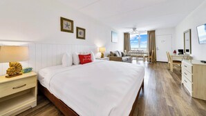 Une chambre d’hôtel avec un grand lit, un bureau, une chaise, une table de chevet et une fenêtre donnant sur le ciel.