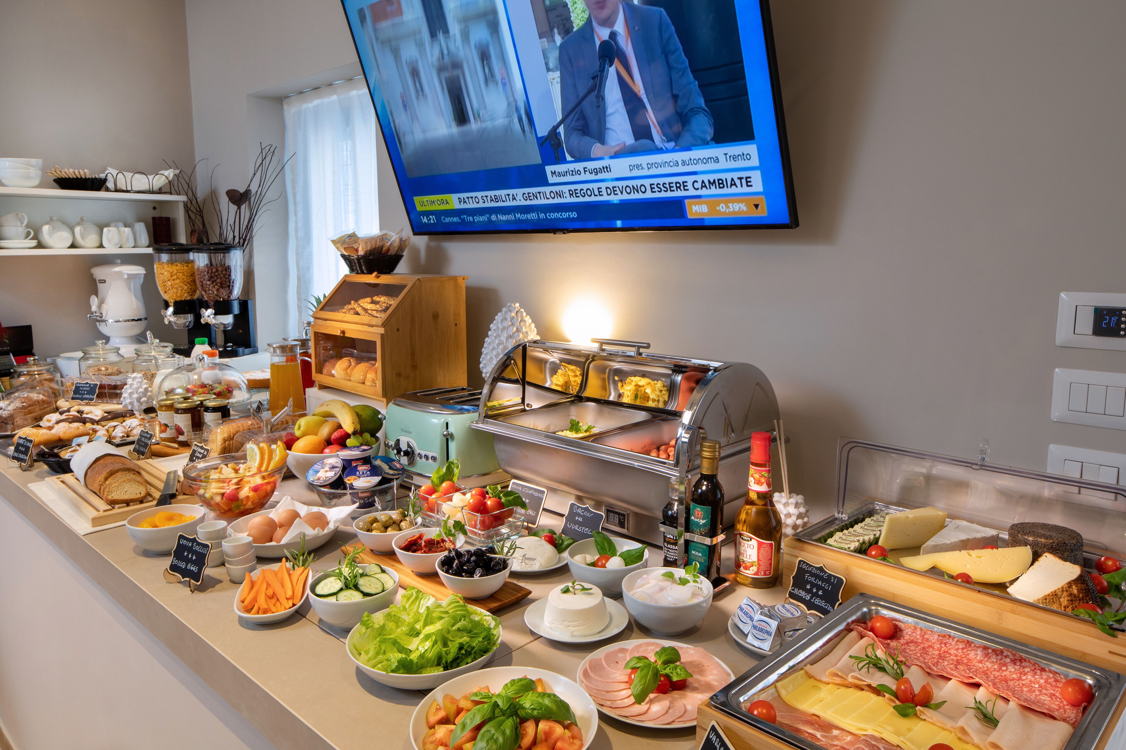 A buffet with various food items and a television displaying a news broadcast.