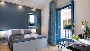 A modern hotel room with a bed, bedside tables, a desk with a chair, a balcony with blue railings, and a view of the outside. - Casa Blandano (Castelmola)