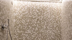 A small, tiled shower area with a bench and a towel. - Casa Blandano (Castelmola)