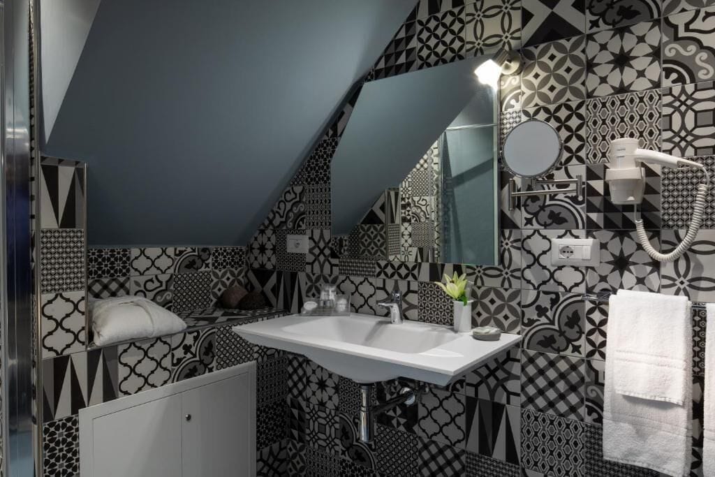 Un baño con lavamanos blanco, un espejo y un secador de pelo en la pared.