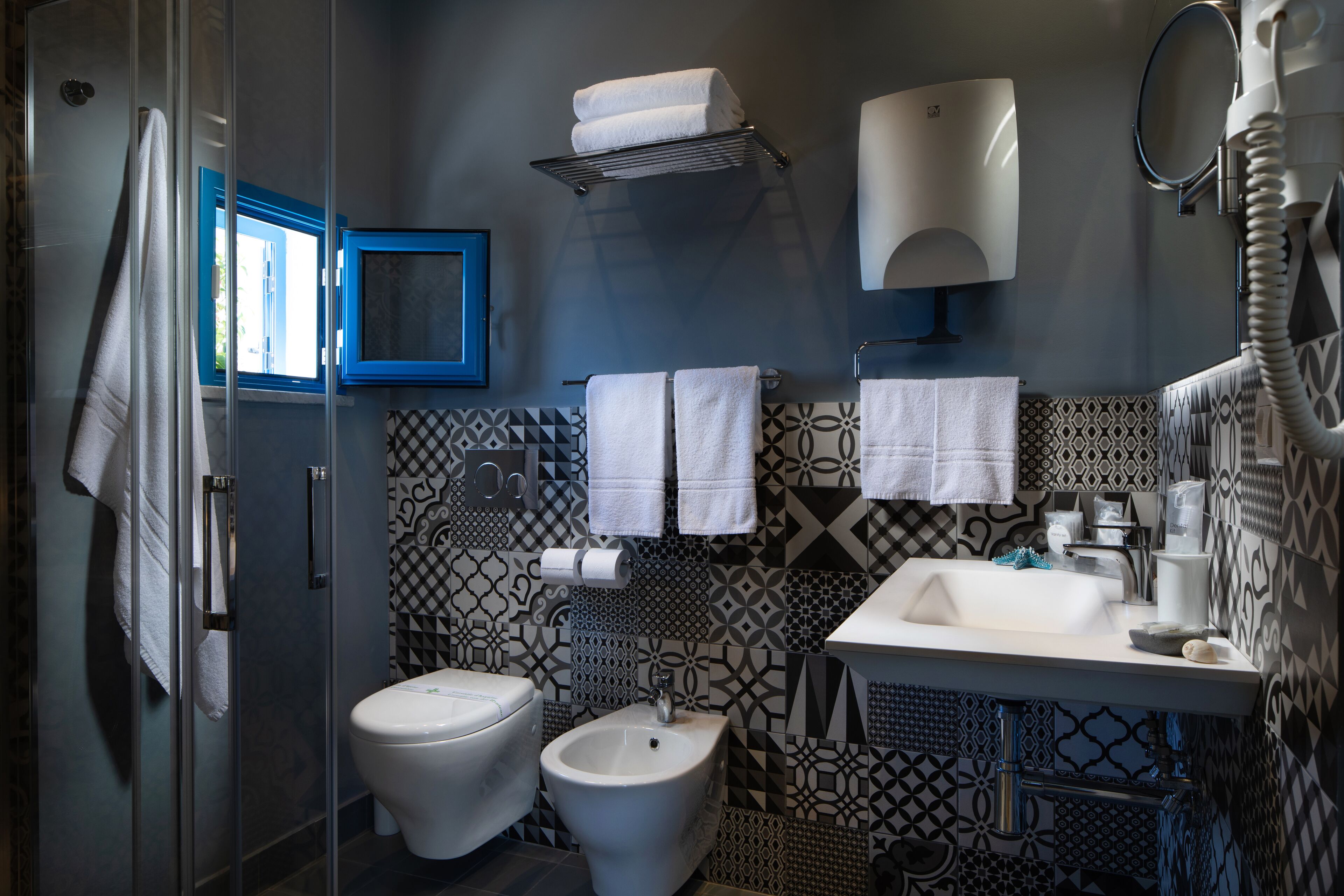 Un baño con inodoro, bidé, lavamanos y perchero para toallas.