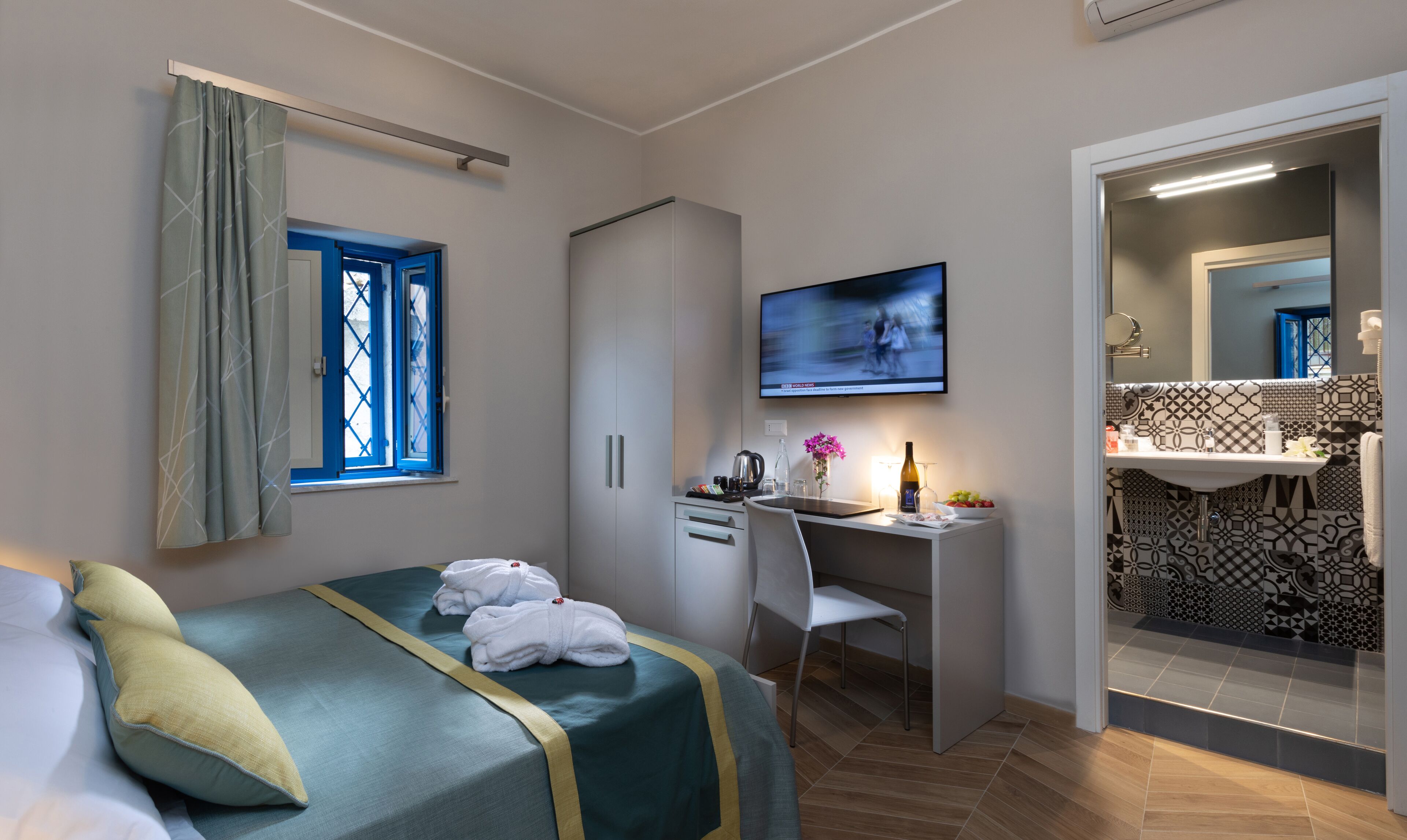 Una habitación de hotel con cama, escritorio, televisión y baño.