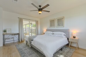 A bedroom with a bed, bedside tables, a desk, and a ceiling fan.