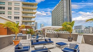 A rooftop terrace with outdoor seating, a grill, and potted plants. - Midtown Miami 2-BD | Pool+Sauna | Gym | Mini Golf (Miami)