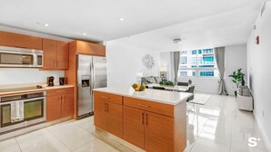 A modern kitchen with stainless steel appliances, wooden cabinets, and a central island. - Midtown Miami 2-BD | Pool+Sauna | Gym | Mini Golf (Miami)