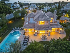 Une grande maison avec une piscine, plusieurs balcons et un jardin bien entretenu.