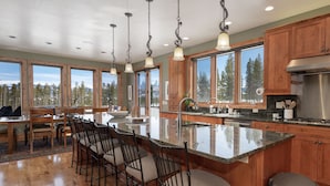 A spacious kitchen with a large island, wooden cabinets, and a view of the forest. - Family-friendly cabin near Winter Park w/ hot tub (Fraser)