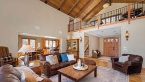 A spacious living room with leather sofas, a wooden coffee table, and a high ceiling with exposed beams. - Family-friendly cabin near Winter Park w/ hot tub (Fraser)
