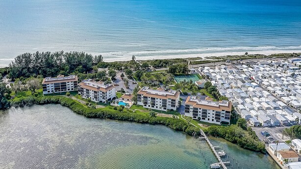 Ein Luftbild eines Küstenhotels mit mehreren Gebäuden, einer Marina und einem Strand.