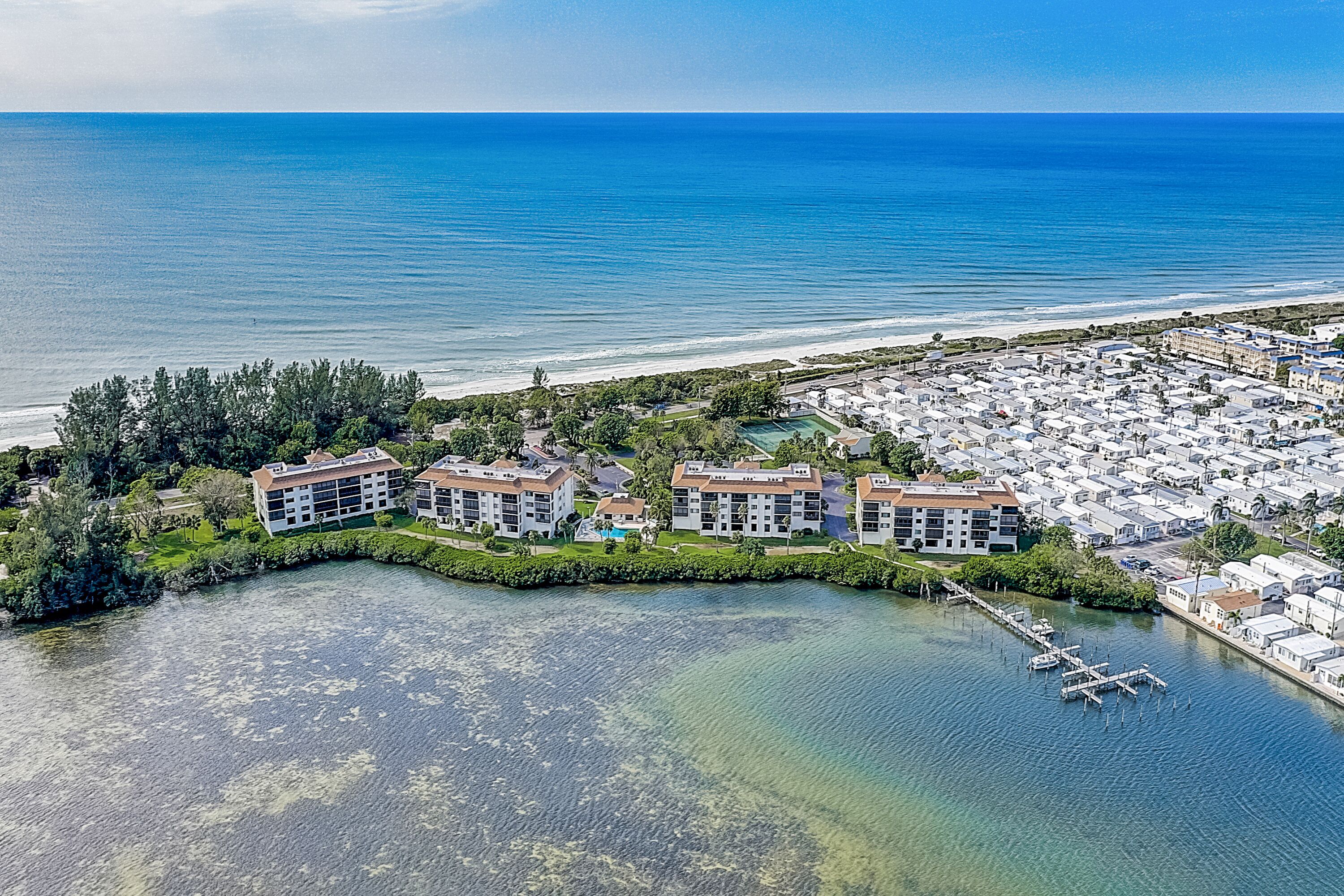 Ein Luftbild eines Küstenresorts mit mehreren Gebäuden, einer Marina und einem Strand.