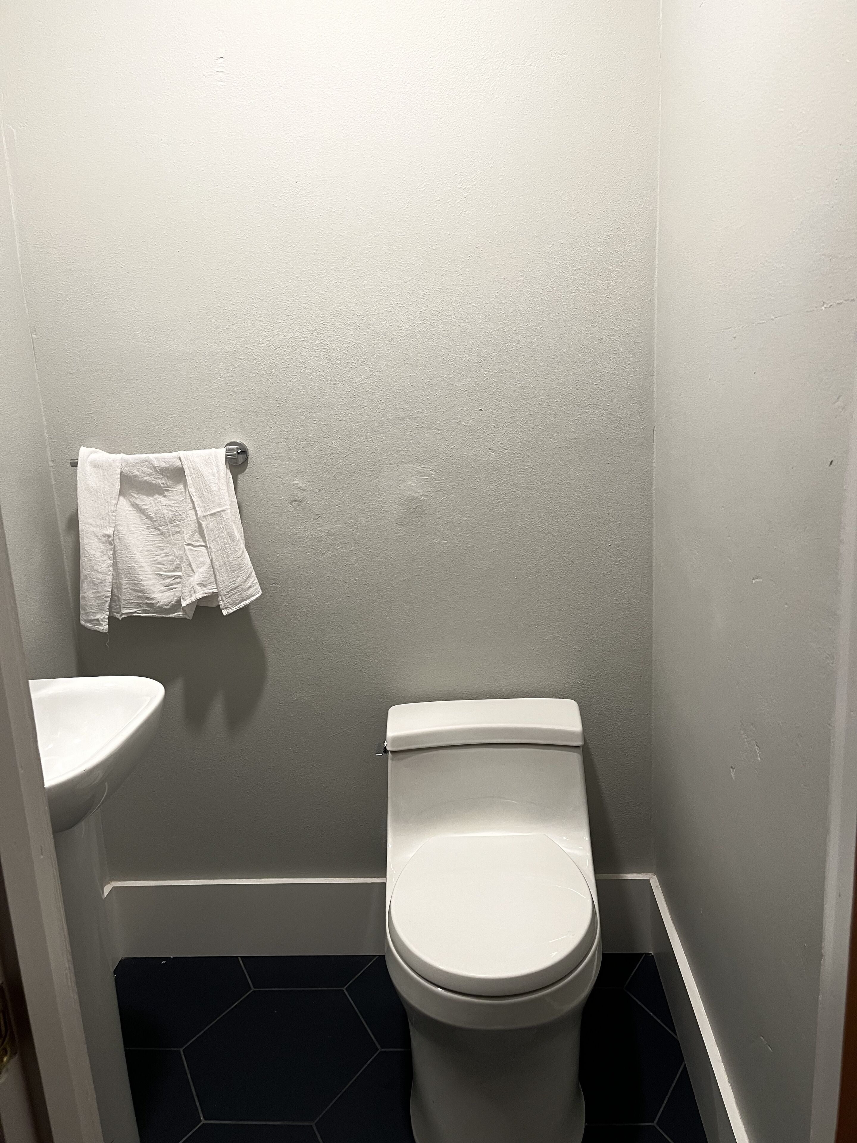 Ein kleines Badezimmer mit Toilette, Waschbecken und einem Handtuch, das an der Wand hängt.