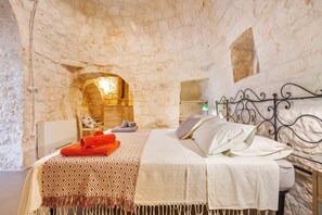 A stone-walled bedroom with a bed, pillows, and a blanket.