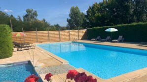A swimming pool with a wooden deck, lounge chairs, and a hedge. - Gîte in the heart of the Périgord Noir in a green, peaceful setting  (Saint-Crépin-et-Carlucet)