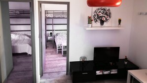 A modern living room with a black entertainment unit, a red pendant light, and a small table. - Gîte in the heart of the Périgord Noir in a green, peaceful setting  (Saint-Crépin-et-Carlucet)
