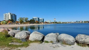 Ein Park am Seeufer mit großen Felsen, einem Spielplatz und Hochhäusern im Hintergrund.