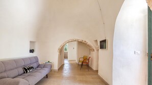 A hallway with a sofa, chairs, and an archway leading to another room. - 2499 Trulli La Meringa by Perle di Puglia (Ostuni)