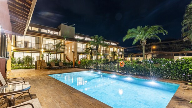 A modern hotel with a swimming pool, outdoor seating, and lush landscaping. - Anoa Maresias Studios (São Sebastião)