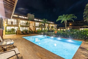 A modern hotel with a swimming pool, outdoor seating, and lush landscaping. - Anoa Maresias Studios (São Sebastião)
