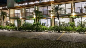 A multi-story hotel with balconies, large windows, and a paved walkway. - Anoa Maresias Studios (São Sebastião)