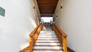 A wooden staircase with white steps leading to a covered area. - Anoa Maresias Studios (São Sebastião)